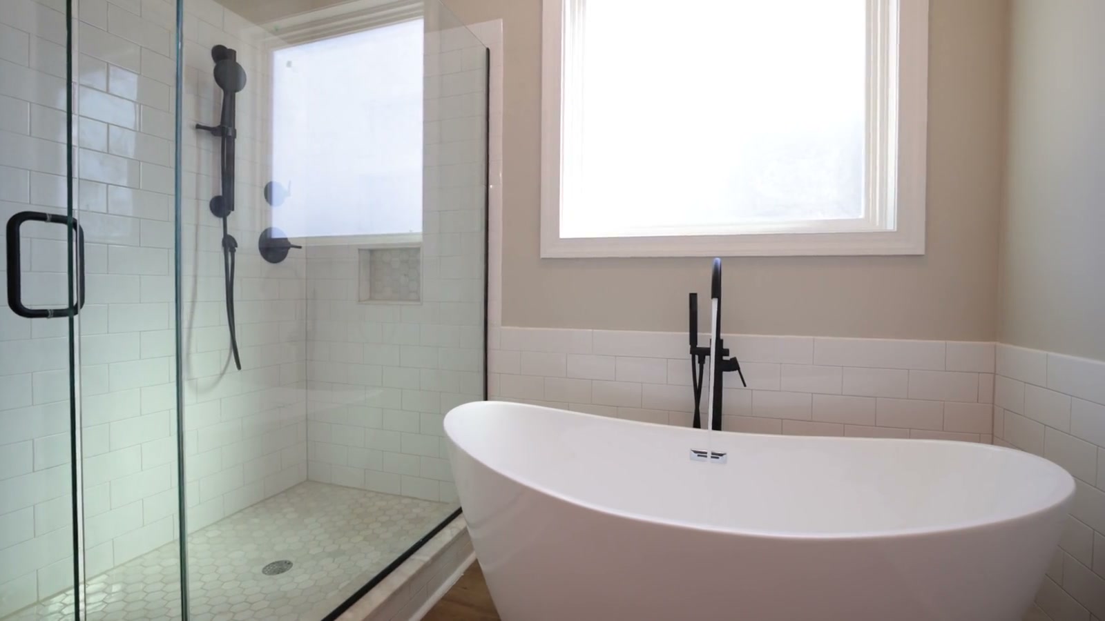 A spacious contemporary bathroom with a freestanding tub, tile and glass shower, shown as remodeling inspiration